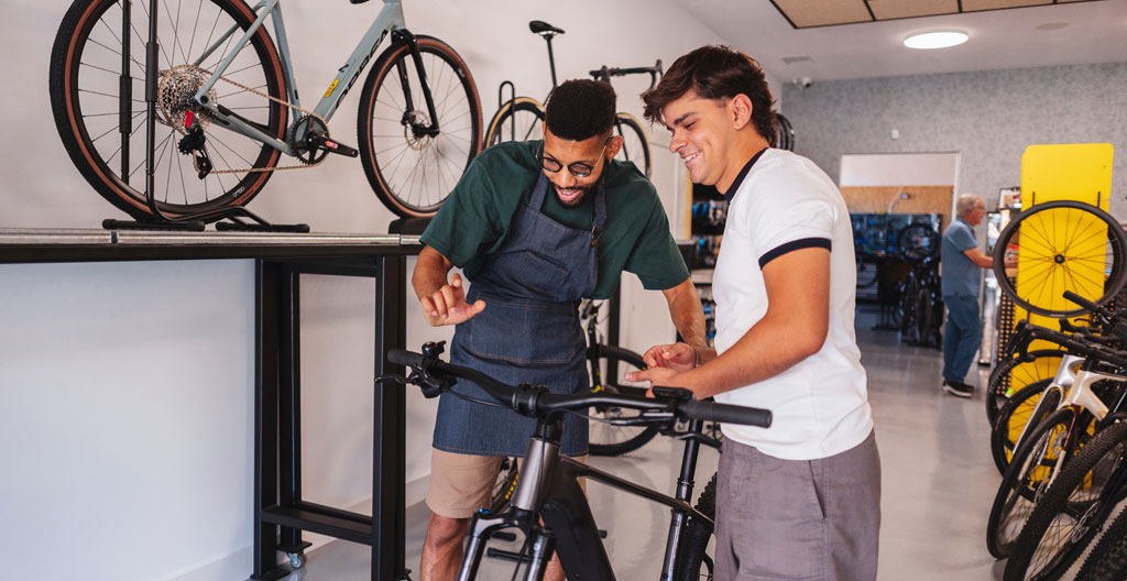 Famille choisissant des vélos dans une agence de location à Annecy avec vélos classiques et électriques en arrière-plan